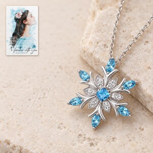 Winter Azure Snowflake Necklace shown in a close macro view highlighting the visible texture, texture and construction details. A personalized digital greeting card is shown alongside.