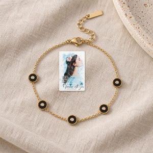 Black Disc Bracelet, laid on fabric. A sample personalized digital greeting card is shown alongside.
