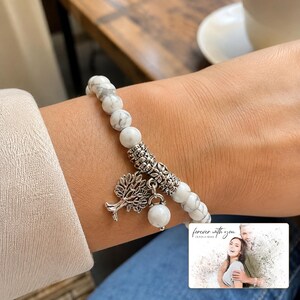 White and gray bead bracelet with silver-tone tree and hanging bead details, adult lifestyle view. A personalized greeting-card example appears in the corner.