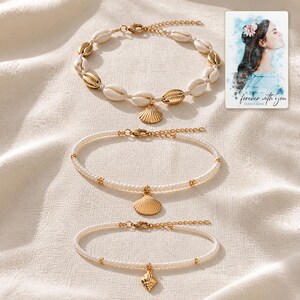 May include: A set of three bracelets featuring a cowrie shell bracelet with gold accents, a pearl-like beaded bracelet with a gold scallop shell charm, and a pearl-like beaded bracelet with a small gold shell charm, plus a card reading forever with you.