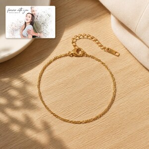 Puede incluir: Una pulsera de cadena en tono dorado con un dise&ntilde;o de eslabones finos, una cadena extensora ajustable y un cierre de mosquet&oacute;n. Incluye una peque&ntilde;a tarjeta rectangular con la foto de una pareja y el texto "forever with you".
