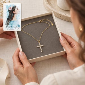 Adult recipient views the Golden cross necklace in an open box above an ivory linen table. A personalized digital greeting card is shown alongside.