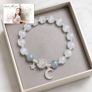 Puede incluir: Una pulsera de cuentas con perlas blancas transl&uacute;cidas y azules iridiscentes, separadores plateados y un dije central de plata con forma de luna y estrella. Incluye una tarjeta con la foto de una pareja y el texto "forever with you".