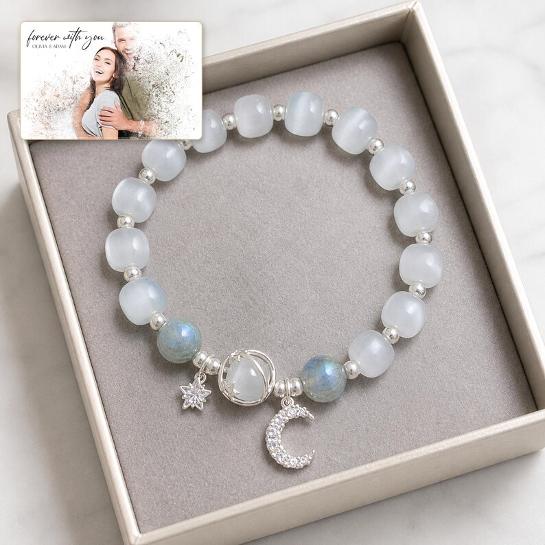 Puede incluir: Una pulsera de cuentas con perlas blancas transl&uacute;cidas y azules iridiscentes, separadores plateados y un dije central de plata con forma de luna y estrella. Incluye una tarjeta con la foto de una pareja y el texto "forever with you".