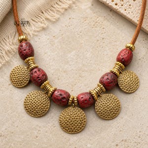 Photo of red beaded gold tone coin charm necklace on a black display bust