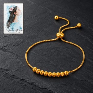 Golden Spiral Bead Slider Bracelet styled against a dark luxury surface with the exact product finish clearly visible. A personalized digital greeting card is shown alongside.