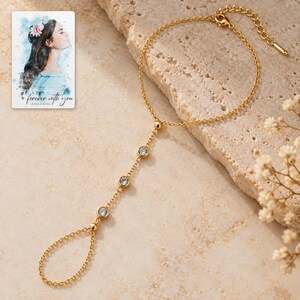 Golden Three stone style Hand Chain shown in a close macro view highlighting the visible texture, texture and construction details. A personalized digital greeting card is shown alongside.
