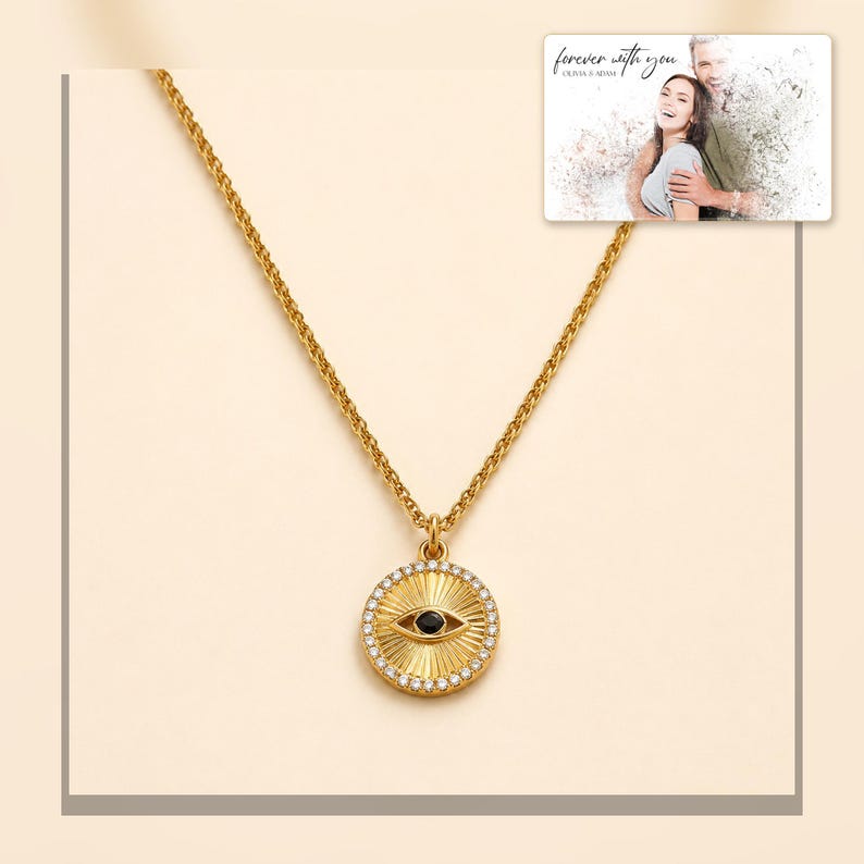 Gold-tone necklace with a round sunburst and black eye detail, framed product view. A personalized greeting-card example appears in the corner.