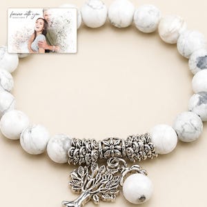 White and gray bead bracelet with silver-tone tree and hanging bead details, close detail view. A personalized greeting-card example appears in the corner.