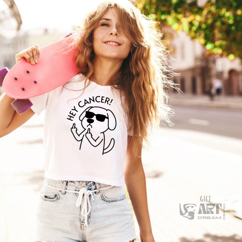 May include: White cropped t-shirt with a black and white illustration of a dog wearing sunglasses and giving the middle finger. The text "Hey Cancer!" is written above the dog.