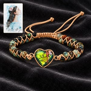 Verdant Heart Woven Bracelet styled against a dark luxury surface with the exact product finish clearly visible. A personalized digital greeting card is shown alongside.