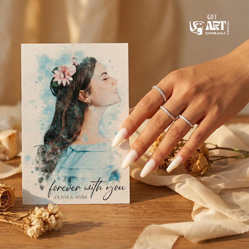 May include: A greeting card with a watercolor portrait of a woman with a flower in her hair, the text "forever with you" and the names Olivia & Adam. The image also shows a hand with four diamond rings.