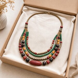Four-strand green coral mustard and antique-brass ethnic necklace worn with an ivory linen top in warm natural window light