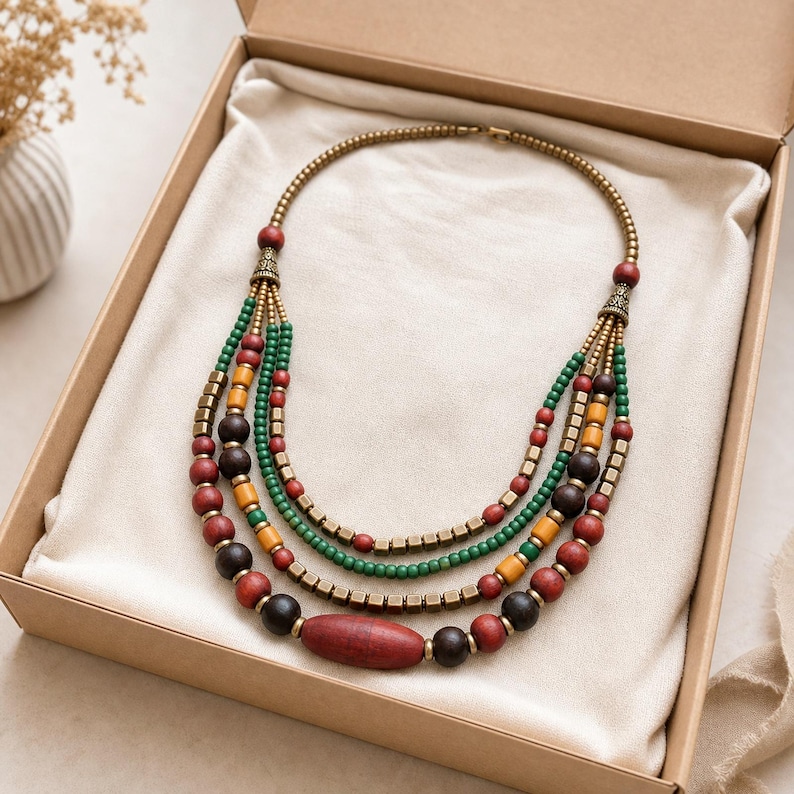 Four-strand green coral mustard and antique-brass ethnic necklace worn with an ivory linen top in warm natural window light