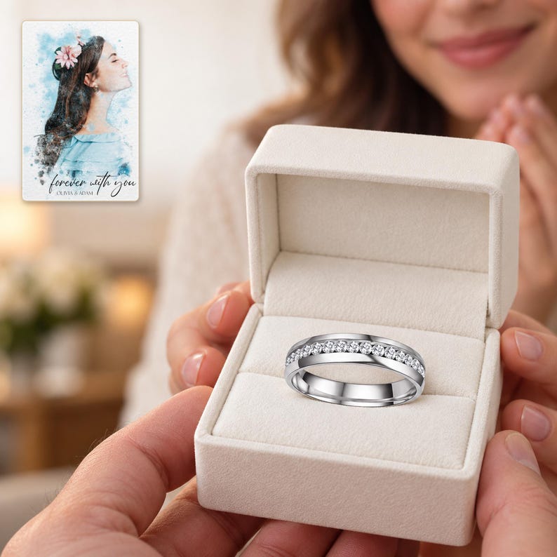 An adult receiving an open ivory ring box with the silver-tone clear-accent band prominent in the foreground. A personalized digital greeting card is shown alongside.
