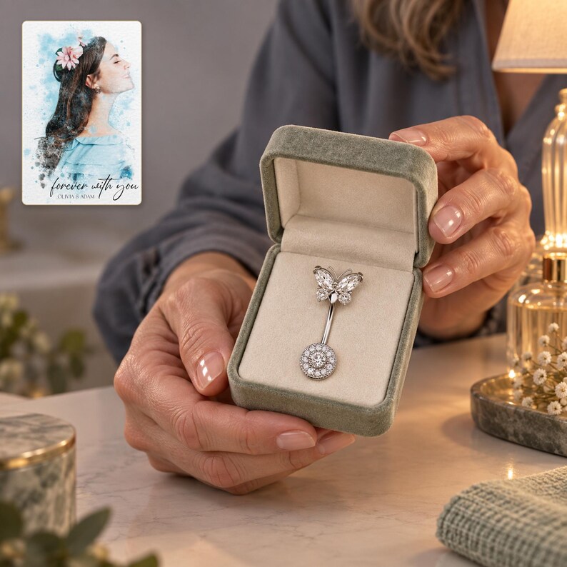 A fully clothed adult presents the butterfly navel bar in an open box near a softly lit evening dressing table. A personalized digital greeting card is shown alongside.