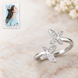 Close view of the ring's two four-wing butterfly motifs with silver tone rims and small clear accents. A personalized digital greeting card is shown alongside.