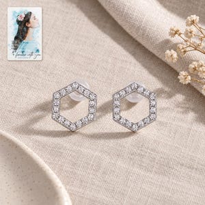 Hexagon Moissanite Stud Earrings, laid on fabric. A sample personalized digital greeting card is shown alongside.