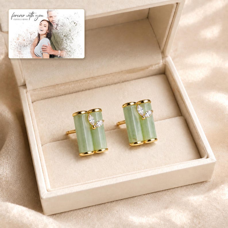 Pale green bamboo-shaped stud earrings with gold-tone edges, presentation in an open jewelry box. A personalized greeting-card example appears in the corner.