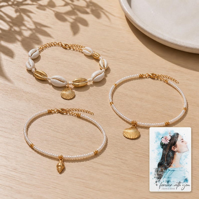 May include: Three bracelets with gold-toned metal shell charms. One bracelet features white cowrie shells and gold-toned shells. Two bracelets consist of small white beads with gold-toned accents. A card shows a watercolor illustration with text.