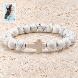 May include: A stretch bracelet featuring round white beads with grey veining and a central horizontal cross-shaped bead. Included is a small rectangular card with an illustration of a person and the text "forever with you" in cursive script.