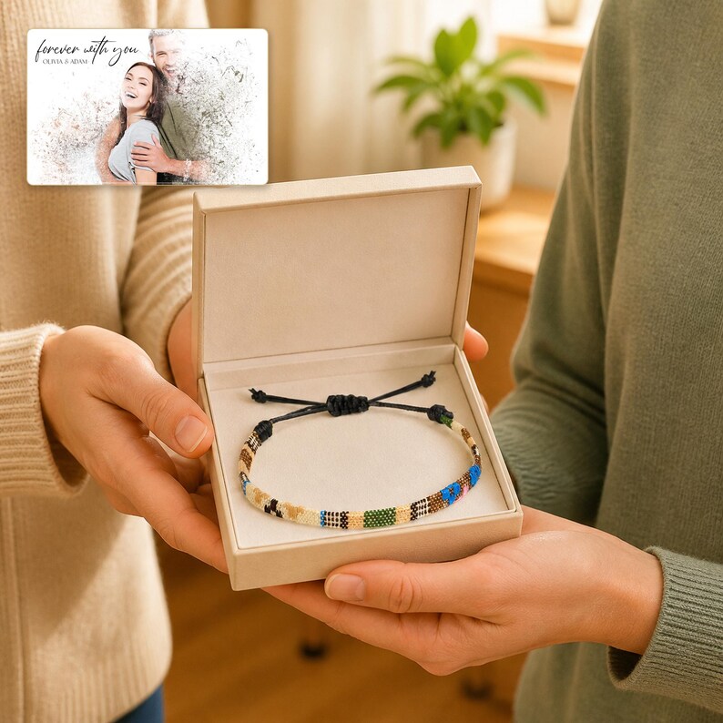 May include: A woven bracelet with a multi-coloured geometric pattern and black adjustable cord strings, presented inside a light beige square gift box. The box lid features a printed photograph of a couple with the text forever with you.