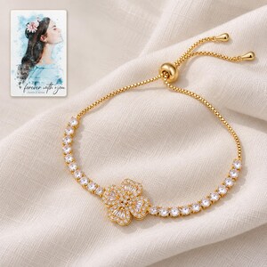 Golden Petal Slider Bracelet arranged on soft ivory linen in a refined neutral flat lay. A personalized digital greeting card is shown alongside.