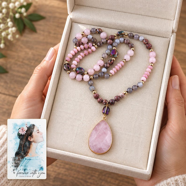 Two adults presenting a gift box containing the Pink option teardrop bead necklace. A personalized digital greeting card is shown alongside.