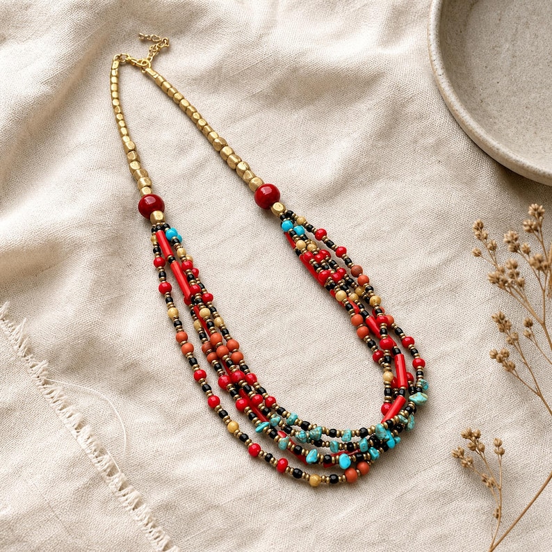 Top down lifestyle view of Red and Brown Statement Beaded Necklace, Boho Handmade Jewelry, Artisan Gift for Her on softly textured ivory linen