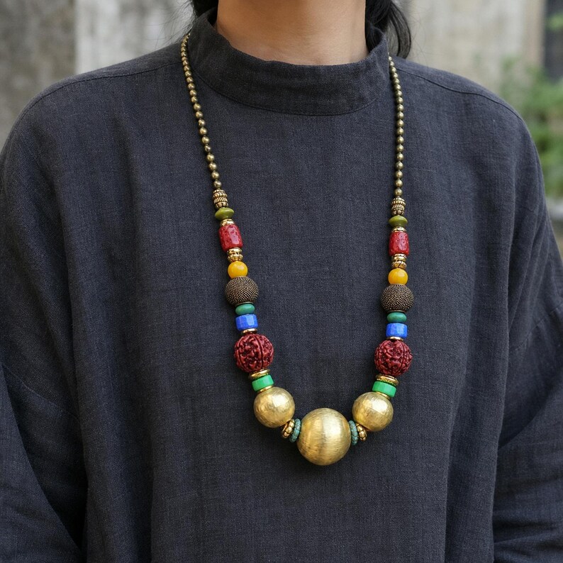 Gift ready presentation of Bold multicolor carved bead and brushed gold sphere necklace in an open jewelry box lined with natural ivory linen