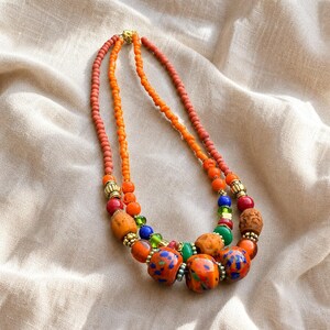 Clear and Orange Statement Beaded Necklace presented in an open jewelry gift box on natural linen