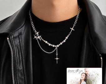 May include: A silver-toned necklace featuring a mix of round white beads and a delicate chain. The design includes star-shaped charms and a central cross pendant. A small rectangular card is visible with the text "forever with you" and "OLIVIA & ADAM".