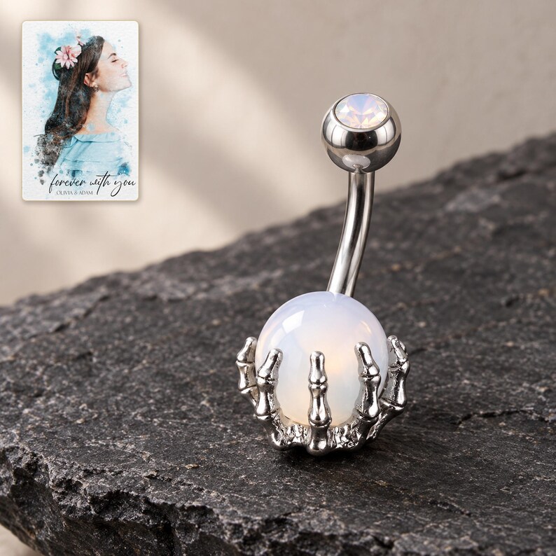 White-ball skeleton-hand barbell displayed on dark slate with polished silver-tone highlights. A personalized digital greeting card is shown alongside.