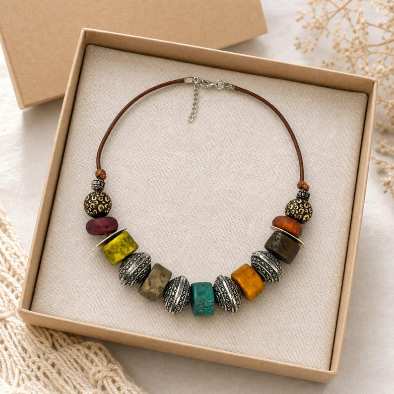 Gift ready presentation of Asymmetric chunky mixed-color necklace with antique-silver engraved beads in an open jewelry box lined with natural ivory linen