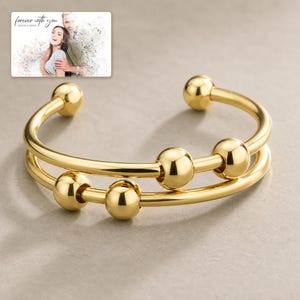 Orbit Five Bead Cuff shown during a warm gift-receiving moment between adults with the exact jewelry visible.