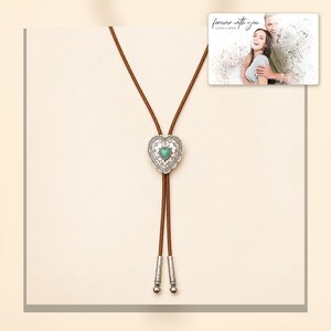 Brown cord bolo necklace with a silver-tone heart slide and turquoise-color center, light-bordered product view. A personalized greeting-card example appears in the corner.