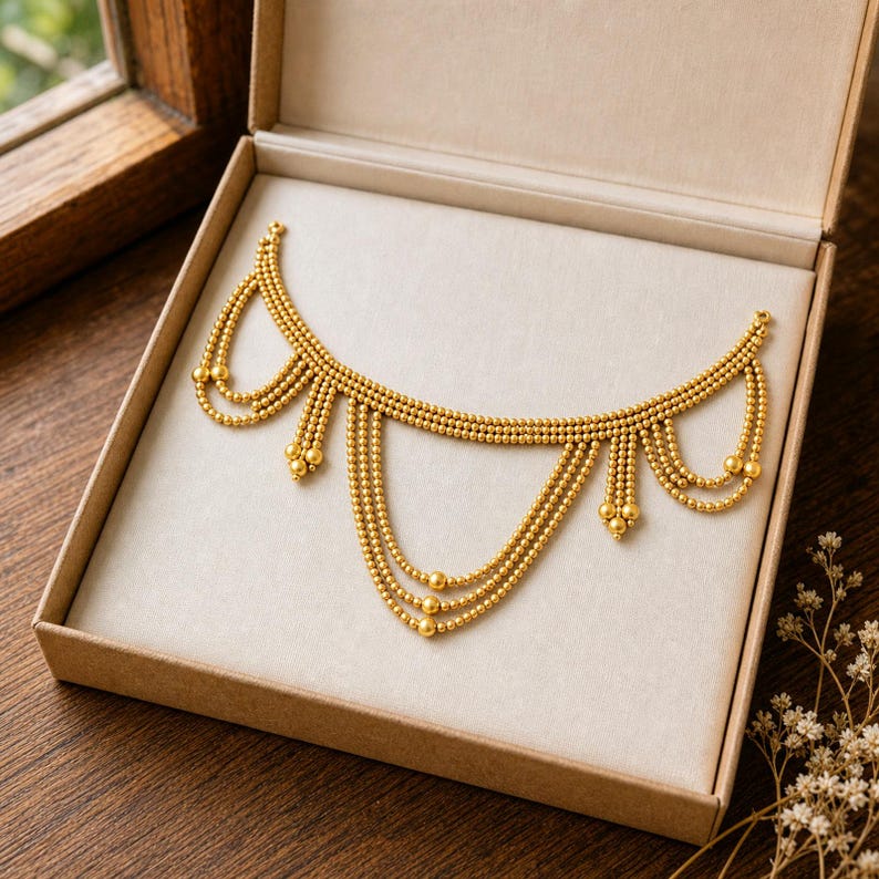 May include: A gold-toned necklace featuring multiple draped strands of small metallic beads. The design consists of a horizontal base chain with several tiered, U-shaped swags hanging downward, each finished with a single larger bead at the ends.