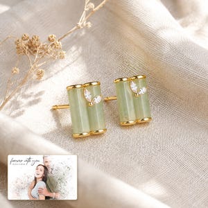 Pale green bamboo-shaped stud earrings with gold-tone edges, framed product view. A personalized greeting-card example appears in the corner.