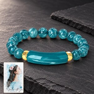 Peacock Tide Bar Bracelet styled against a dark luxury surface with the exact product finish clearly visible. A personalized digital greeting card is shown alongside.