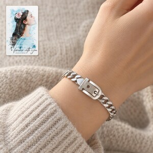 Adult woman's wrist wearing the silver tone belt buckle bracelet with an oatmeal knit sleeve. A personalized digital greeting card is shown alongside.
