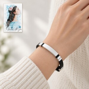 Adult woman wearing the black strap and polished silver-tone bar bracelet with a cream knit sleeve. A personalized digital greeting card is shown alongside.