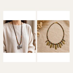 May include: A long necklace featuring small brown, red, and green beads with a large silver-toned elephant pendant, alongside a shorter necklace with gold-toned leaf-shaped charms, small red and green beads, and a metallic chain.