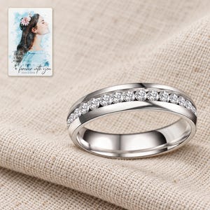 The clear-accent silver-tone band resting on folded oatmeal linen in soft daylight. A personalized digital greeting card is shown alongside.