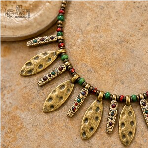 Three-piece handmade necklace set featuring antique gold leaf charm beaded necklace, red beaded coin charm beaded necklace and brown and gray beaded necklace, displayed together to show the coordinated colors and beadwork
