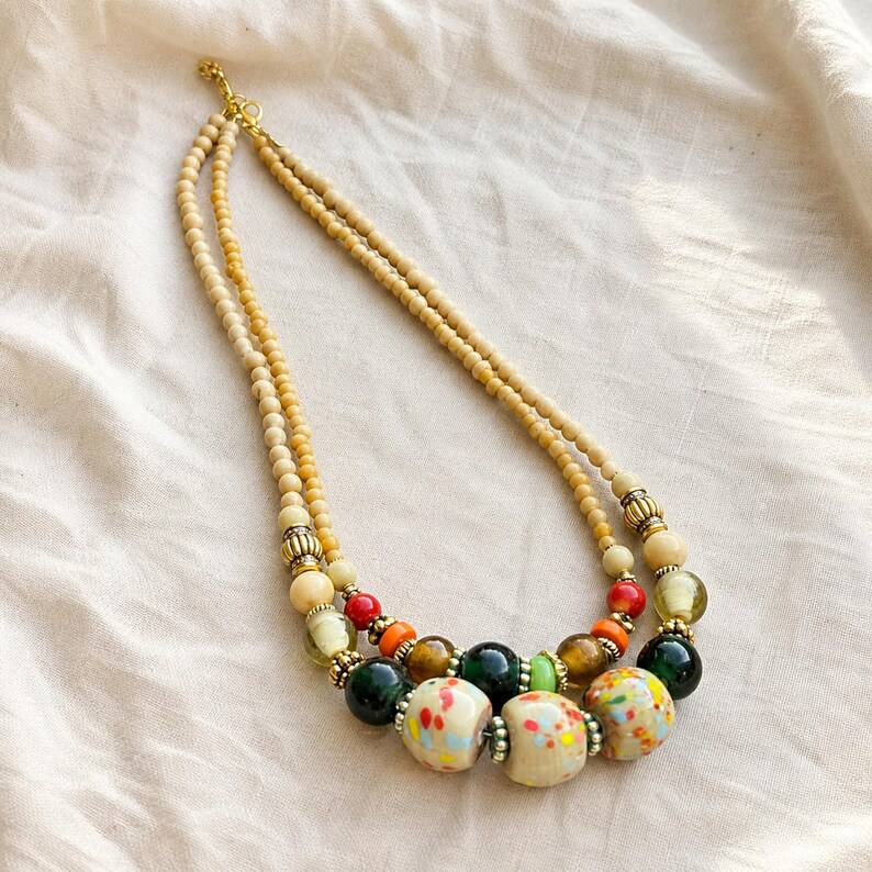 Clear and Beige Statement Beaded Necklace presented in an open jewelry gift box on natural linen