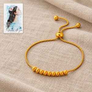 Golden Spiral Bead Slider Bracelet arranged on soft ivory linen in a refined neutral flat lay. A personalized digital greeting card is shown alongside.