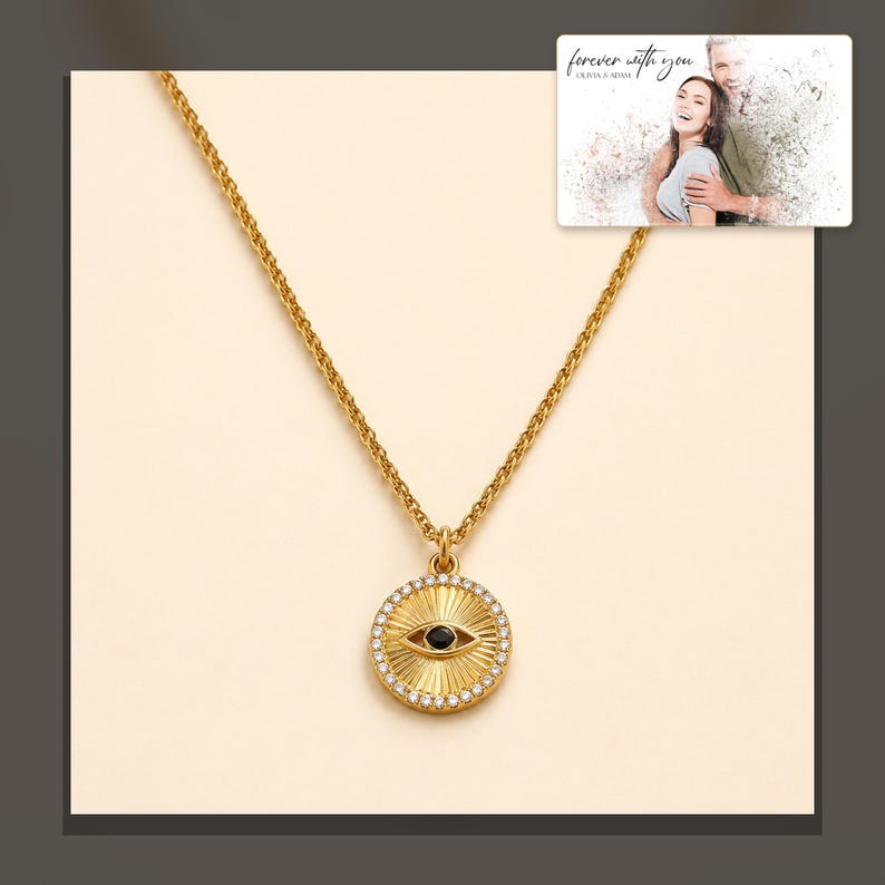 Gold-tone necklace with a round sunburst and black eye detail, dark-bordered product view. A personalized greeting-card example appears in the corner.