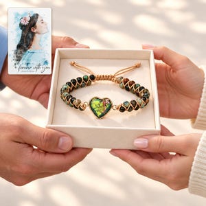 Verdant Heart Woven Bracelet shown during a believable gift-giving moment between adults with the jewelry visible. A personalized digital greeting card is shown alongside.