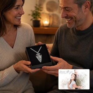 May include: A silver-toned arrowhead pendant necklace displayed inside a black gift box. The pendant features an intricate, textured design and hangs from a matching silver chain. A small rectangular card with the text "forever with you" is included.