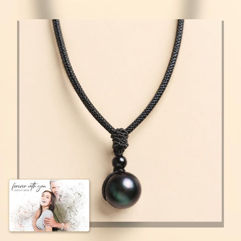 Black cord necklace with a dark round pendant, light-bordered product view. A personalized greeting-card example appears in the corner.